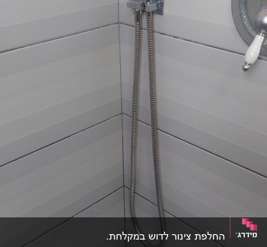 ראש מקלחת עם צינור מתכת בחדר אמבטיה